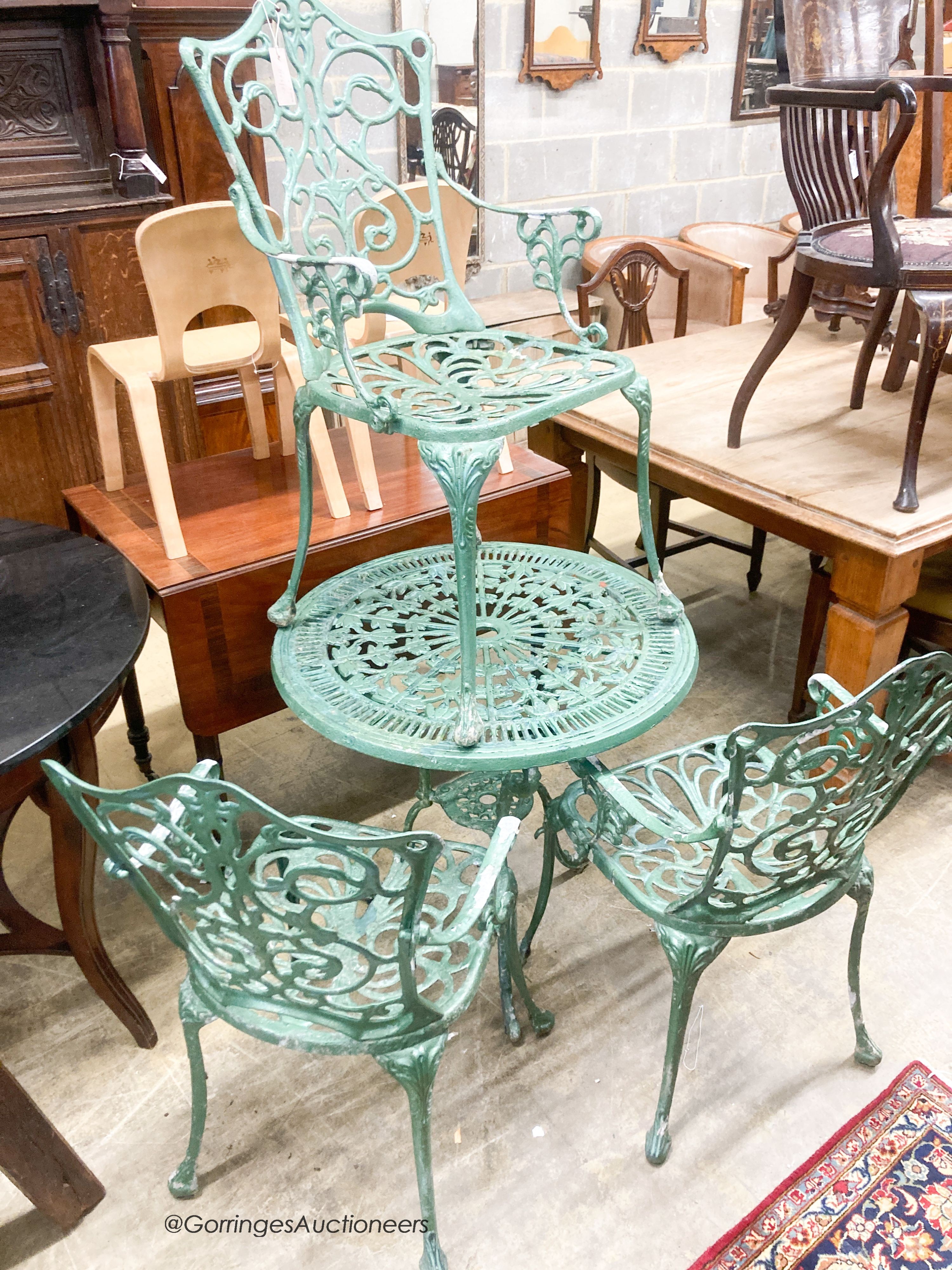 A cast painted aluminium circular garden table, diameter 69cm together with three similar elbow chairs